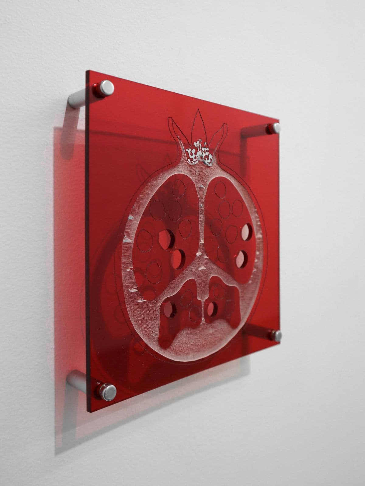 Forbidden Fruit, wall-mounted transparent red acrylic pomegranate by Grigorios Ilaridis with missing seeds referencing temptation and Greek mythology.